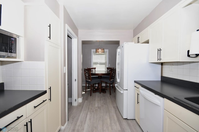 1253 3rd St N, Fargo, ND 58102 - kitchen featuring white appliances, dark countertops, light wood-style flooring, white cabinetry, and decorative backsplash