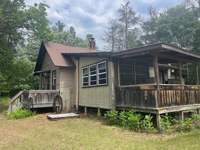 2750 330th St, Sterling Twp, WI 54840 - back of property with a wooden deck, a chimney, roof with shingles, and a yard