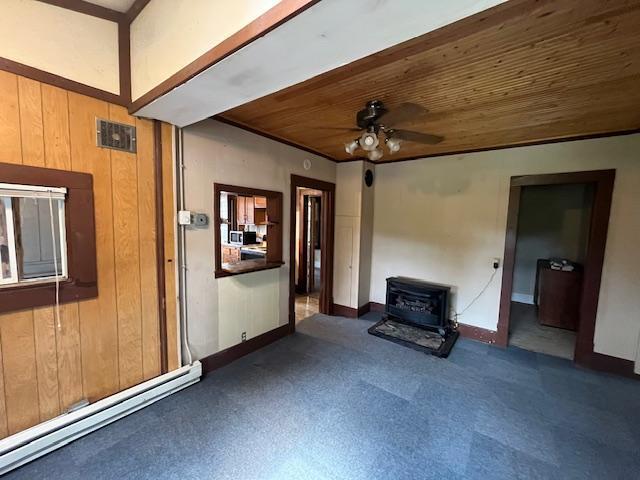 2750 330th St, Sterling Twp, WI 54840 - unfurnished living room with a wood stove, wooden ceiling, a baseboard radiator, a ceiling fan, and carpet flooring