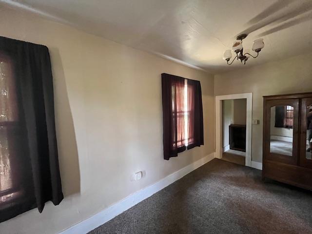 2750 330th St, Sterling Twp, WI 54840 - spare room featuring a chandelier and dark colored carpet