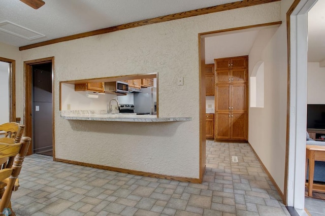 604 2nd Ave S, Kindred, ND 58052 - kitchen with brick patterned floors, appliances with stainless steel finishes, light countertops, a textured wall, and brown cabinets