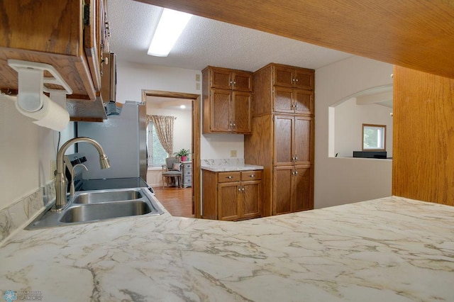 604 2nd Ave S, Kindred, ND 58052 - kitchen featuring brown cabinets, arched walkways, light countertops, and wood finished floors