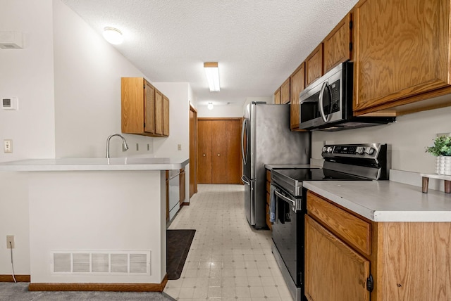 930 106th Ln NW Unit 9Nw, Coon Rapids, MN 55433 - kitchen featuring black electric range oven, stainless steel microwave, a textured ceiling, brown cabinetry, and light countertops