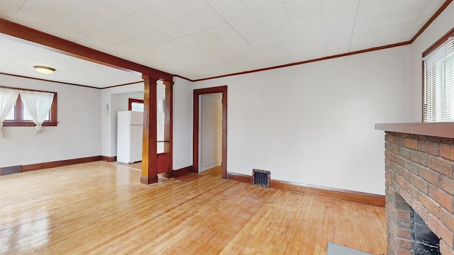 1038 23rd Ave SE, Minneapolis, MN 55414 - unfurnished living room with hardwood / wood-style floors, crown molding, a fireplace, and decorative columns