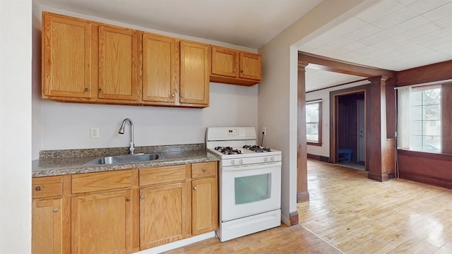 1038 23rd Ave SE, Minneapolis, MN 55414 - kitchen featuring white gas stove, light wood-style floors, dark countertops, and brown cabinets