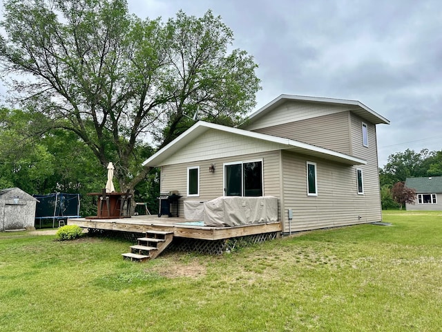 316 2nd St NE, Menahga, MN 56464 - back of property featuring a trampoline, a lawn, a wooden deck, and a storage unit
