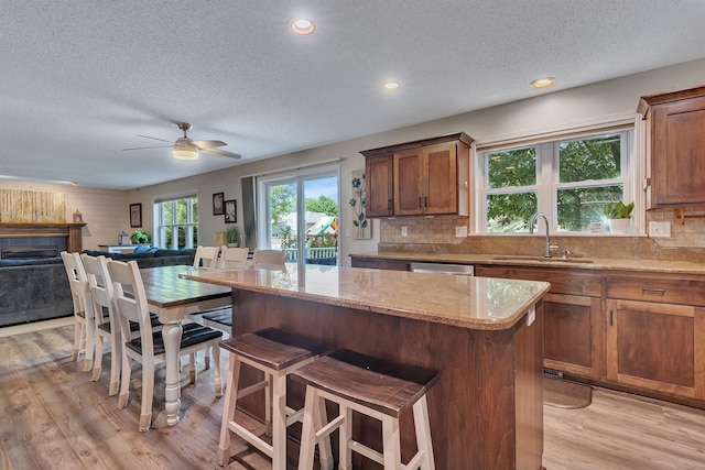 2668 Waterford Ct, Saint Cloud, MN 56301 - kitchen featuring a textured ceiling, light wood finished floors, open floor plan, light stone counters, and a center island