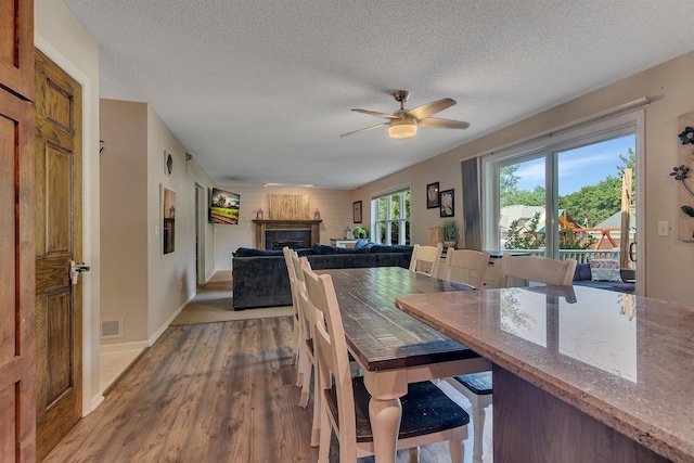 2668 Waterford Ct, Saint Cloud, MN 56301 - dining room with wood finished floors, a fireplace, a ceiling fan, and a textured ceiling