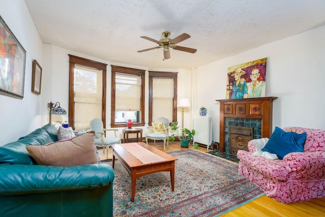 63 Avon St S Unit 36, Saint Paul, MN 55105 - living area featuring radiator heating unit, wood finished floors, ceiling fan, a tile fireplace, and a textured ceiling