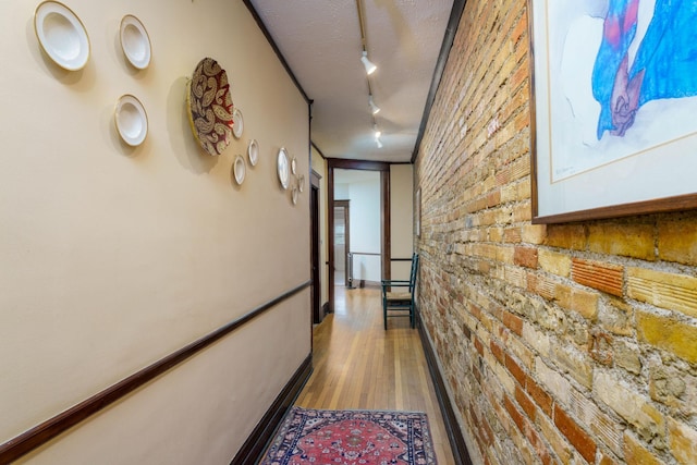 63 Avon St S Unit 36, Saint Paul, MN 55105 - hallway featuring track lighting, brick wall, and wood finished floors