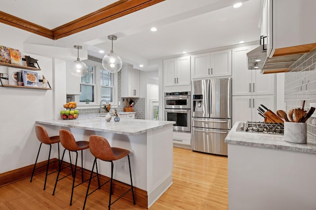 4708 Pleasant Ave, Minneapolis, MN 55419 - kitchen featuring appliances with stainless steel finishes, decorative backsplash, a peninsula, white cabinets, and a breakfast bar area