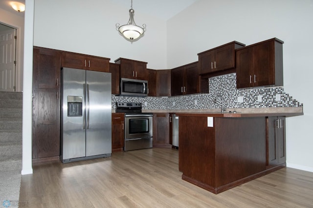 1381 Westport Beach Way W, Fargo, ND 58078 - kitchen with stainless steel appliances, light wood-style flooring, tasteful backsplash, dark brown cabinetry, and high vaulted ceiling