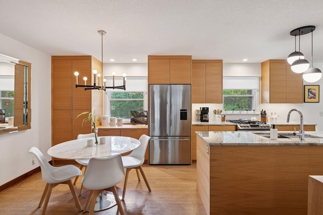 18201 Kathleene Dr, Minnetonka, MN 55345 - kitchen with appliances with stainless steel finishes, modern cabinets, brown cabinetry, light wood finished floors, and light stone counters