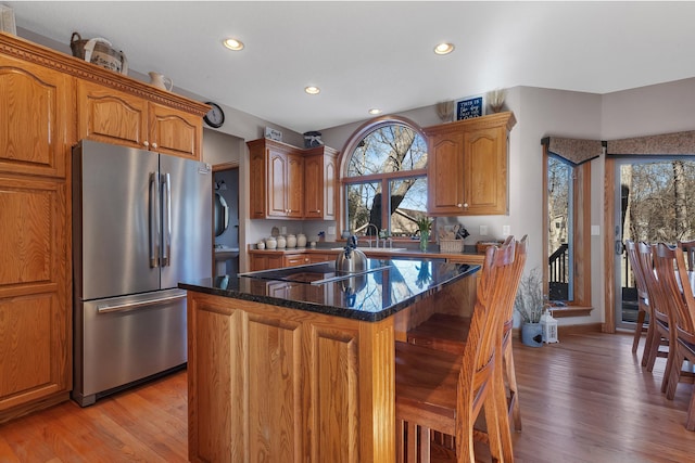 617 17th St N, Sartell, MN 56377 - kitchen featuring freestanding refrigerator, black electric stovetop, light wood-type flooring, a breakfast bar area, and a center island