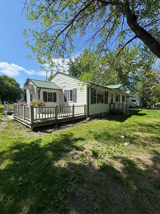 413 3rd Ave SE, Baudette, MN 56623 - rear view of property featuring a lawn, a metal roof, and a wooden deck