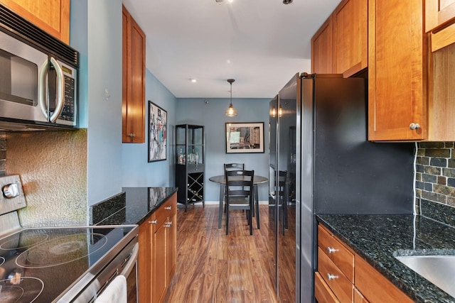 3131 Excelsior Blvd Unit 508, Minneapolis, MN 55416 - kitchen with appliances with stainless steel finishes, wood finished floors, tasteful backsplash, brown cabinetry, and dark stone countertops