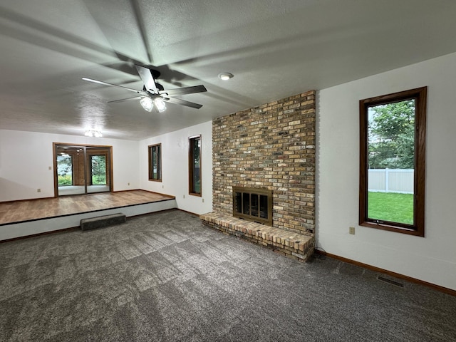 605 Arbor Ct, Marshall, MN 56258 - unfurnished living room featuring ceiling fan, healthy amount of natural light, carpet flooring, a fireplace, and a textured ceiling