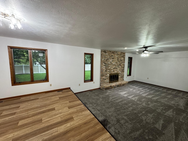 605 Arbor Ct, Marshall, MN 56258 - unfurnished living room with wood finished floors, healthy amount of natural light, a textured ceiling, ceiling fan, and a brick fireplace