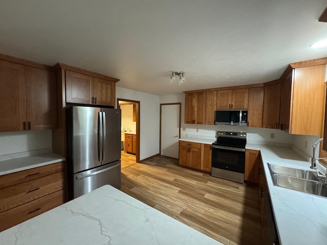 605 Arbor Ct, Marshall, MN 56258 - kitchen with appliances with stainless steel finishes, light wood-style flooring, brown cabinetry, and light stone counters