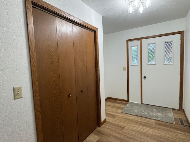 605 Arbor Ct, Marshall, MN 56258 - foyer with light wood-type flooring, a textured wall, and a textured ceiling