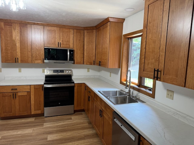 605 Arbor Ct, Marshall, MN 56258 - kitchen with stainless steel appliances, brown cabinets, light countertops, and light wood-style floors