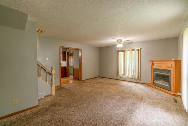 421 Moore St, Blue Earth, MN 56013 - unfurnished living room with carpet flooring, ceiling fan, a glass covered fireplace, a textured ceiling, and stairway