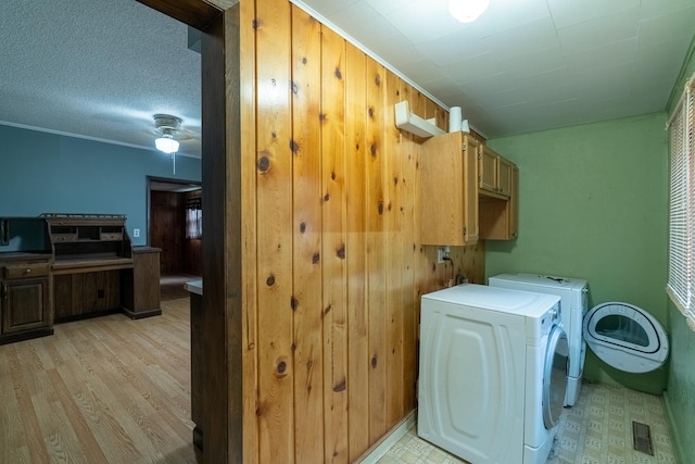 421 Moore St, Blue Earth, MN 56013 - washroom with cabinet space, independent washer and dryer, light wood-style floors, wood walls, and a ceiling fan