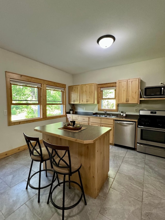 2795 40th St NW, Hackensack, MN 56452 - kitchen featuring appliances with stainless steel finishes, dark countertops, a kitchen bar, and light brown cabinets