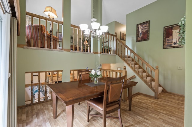 6469 Deerwood Ln N, Maple Grove, MN 55369 - dining space featuring a chandelier, wood finished floors, a towering ceiling, and stairway