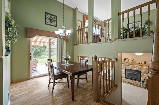 6469 Deerwood Ln N, Maple Grove, MN 55369 - dining space with a towering ceiling, a chandelier, wood finished floors, and a brick fireplace