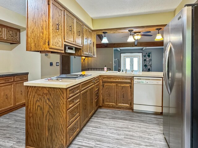 607 1st St, Marshall, MN 56258 - kitchen with freestanding refrigerator, white dishwasher, stovetop, a ceiling fan, and brown cabinets