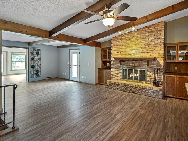 607 1st St, Marshall, MN 56258 - unfurnished living room with wood finished floors, a textured ceiling, ceiling fan, beam ceiling, and a baseboard heating unit