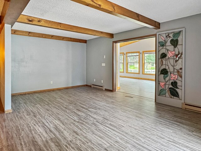 607 1st St, Marshall, MN 56258 - unfurnished room featuring a baseboard heating unit, beamed ceiling, wood finished floors, and a textured ceiling