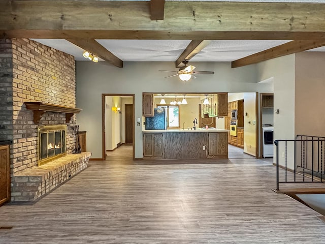 607 1st St, Marshall, MN 56258 - unfurnished living room with wood finished floors, a ceiling fan, beam ceiling, and a fireplace