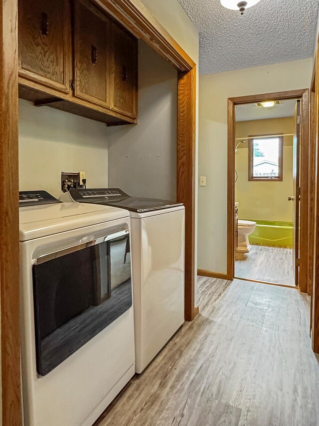 607 1st St, Marshall, MN 56258 - laundry area with cabinet space, washing machine and dryer, light wood-type flooring, and a textured ceiling