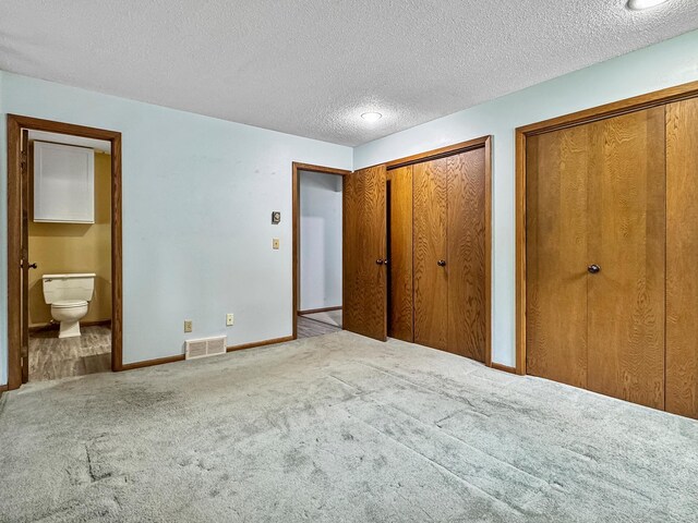 607 1st St, Marshall, MN 56258 - unfurnished bedroom featuring two closets, carpet floors, ensuite bath, and a textured ceiling