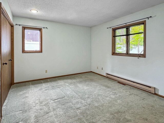607 1st St, Marshall, MN 56258 - unfurnished bedroom with a baseboard heating unit, multiple windows, carpet flooring, a textured ceiling, and a closet