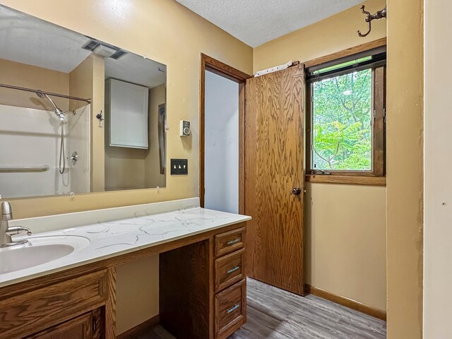 607 1st St, Marshall, MN 56258 - full bath with vanity, wood finished floors, a textured ceiling, and washtub / shower combination