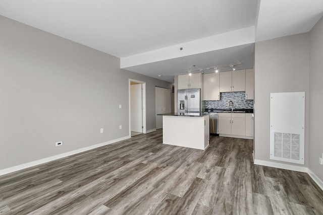 929 Portland Ave Unit 2106, Minneapolis, MN 55404 - kitchen with appliances with stainless steel finishes, dark countertops, rail lighting, dark wood-style flooring, and a center island