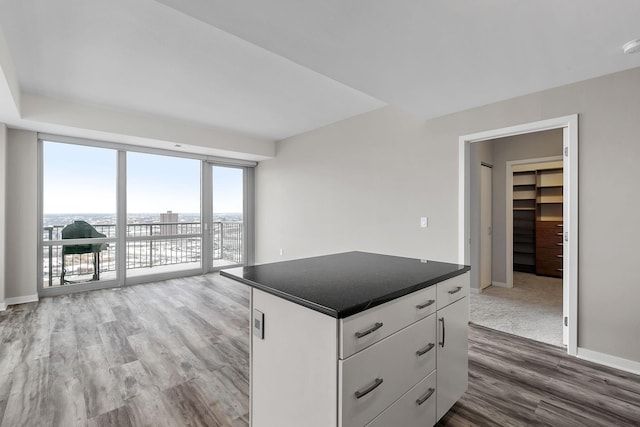 929 Portland Ave Unit 2106, Minneapolis, MN 55404 - kitchen with wood finished floors, dark countertops, white cabinetry, a center island, and open floor plan