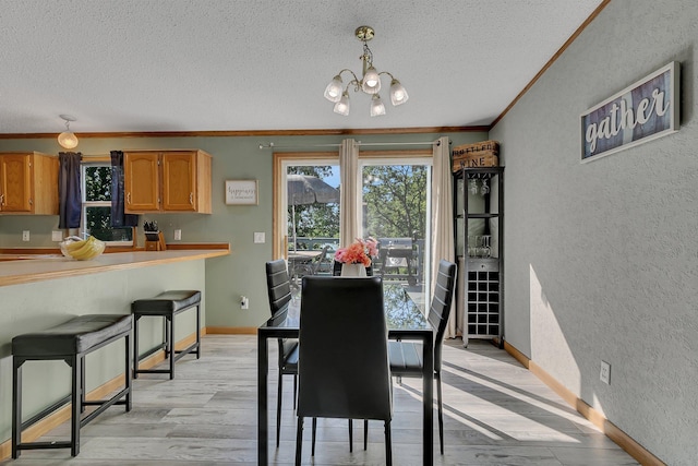 57975 226th St, Litchfield, MN 55355 - dining area with a textured wall, a textured ceiling, a chandelier, ornamental molding, and light wood-type flooring