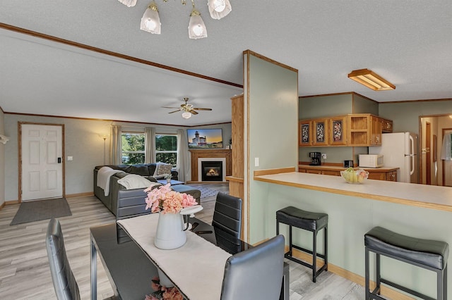 57975 226th St, Litchfield, MN 55355 - dining space featuring light wood finished floors, crown molding, a glass covered fireplace, a ceiling fan, and a textured ceiling