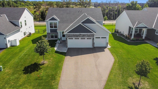 15005 Quintana St NW, Ramsey, MN 55303 - view of front facade with stone siding, asphalt driveway, an attached garage, a front lawn, and roof with shingles