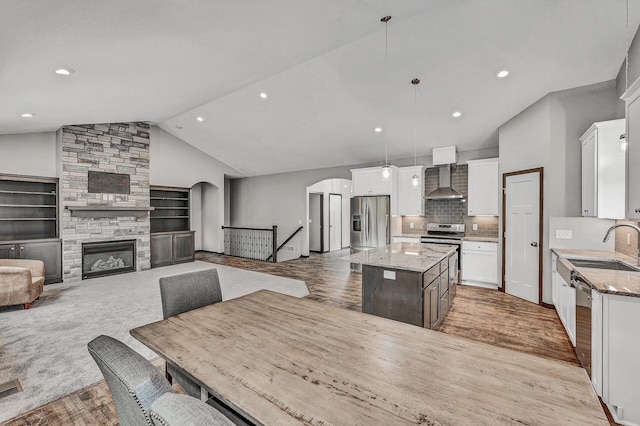 51440 Long Point Pl, Shamrock Twp, MN 55760 - kitchen with wall chimney range hood, stainless steel appliances, lofted ceiling, arched walkways, and a kitchen island