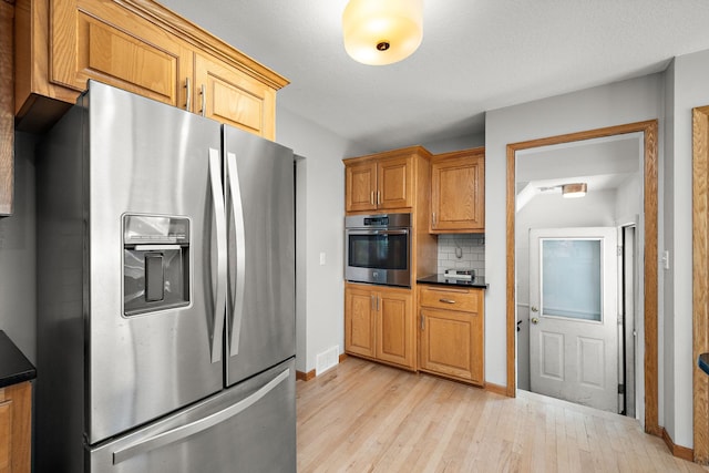 1890 Sheridan Ave, Saint Paul, MN 55116 - kitchen with appliances with stainless steel finishes, light wood-style floors, dark countertops, backsplash, and brown cabinetry