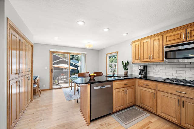1890 Sheridan Ave, Saint Paul, MN 55116 - kitchen with appliances with stainless steel finishes, light wood-type flooring, a peninsula, decorative backsplash, and recessed lighting