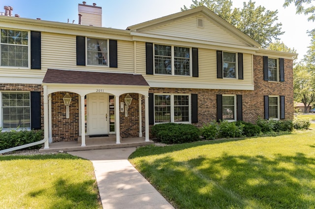 2051 Carriage Dr SW Unit 2051D, Rochester, MN 55902 - view of property with brick siding, a front lawn, a chimney, and covered porch