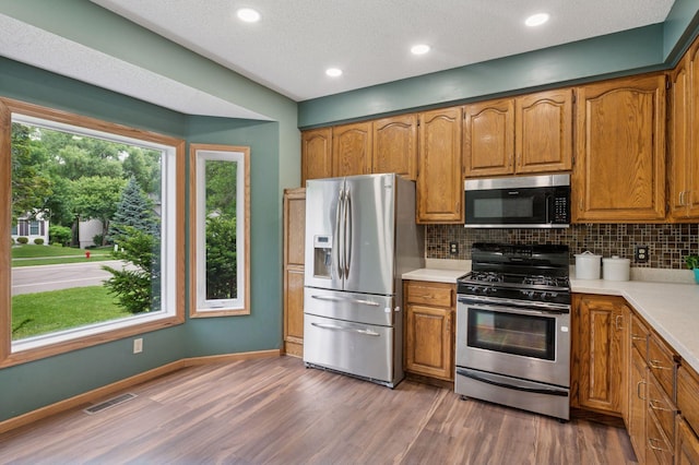 10989 Eagle Lake Blvd, Maple Grove, MN 55369 - kitchen featuring stainless steel appliances, backsplash, light countertops, brown cabinetry, and recessed lighting