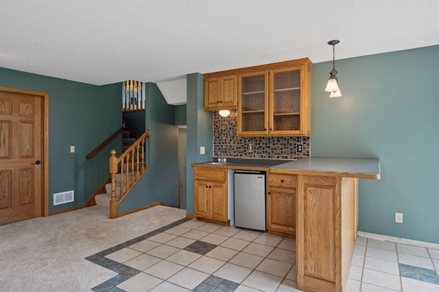 10989 Eagle Lake Blvd, Maple Grove, MN 55369 - kitchen featuring fridge, brown cabinetry, tasteful backsplash, glass insert cabinets, and pendant lighting