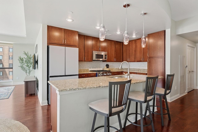 100 3rd Ave S Unit 706, Minneapolis, MN 55401 - kitchen with stainless steel microwave, dark wood finished floors, decorative backsplash, brown cabinetry, and hanging light fixtures